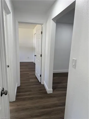 Hall with dark wood-style floors and baseboards