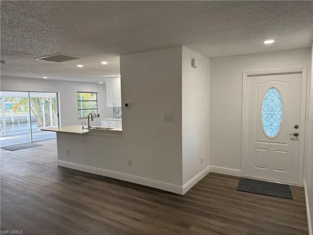 Foyer with a textured ceiling, recessed lighting, and dark wood finished floors