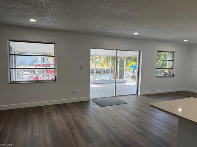 Spare room with a textured ceiling, dark wood-style floors, and recessed lighting