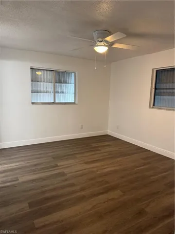 Spare room featuring a textured ceiling, dark wood-style flooring, and ceiling fan