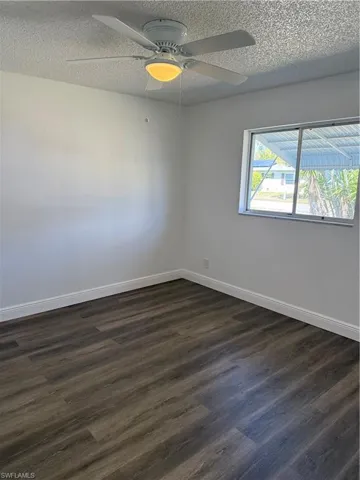 Spare room with ceiling fan, dark wood-style floors, and a textured ceiling