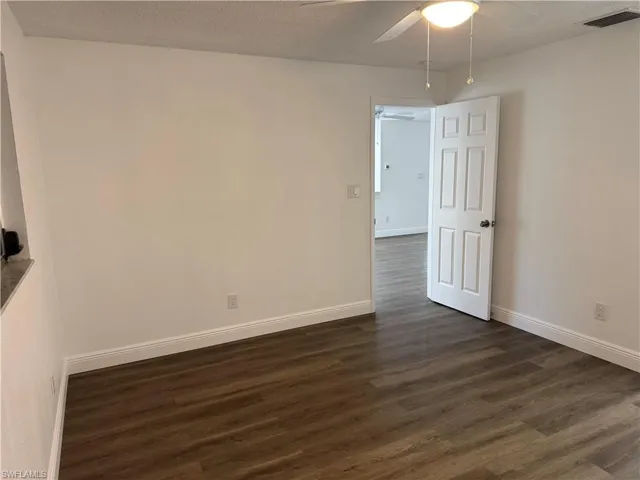 Empty room featuring dark wood-style floors, a textured ceiling, and a ceiling fan