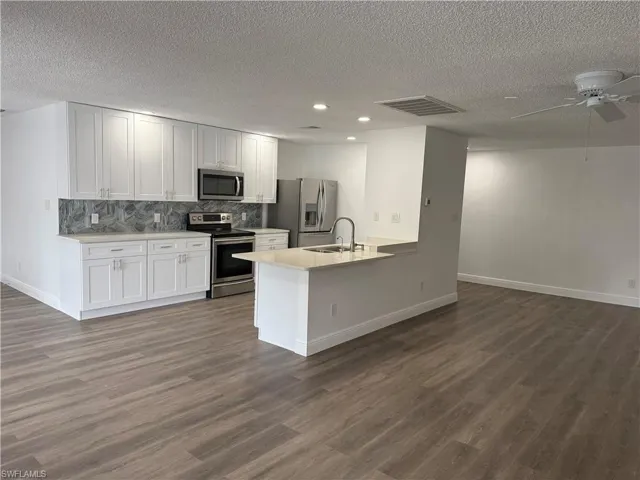 Kitchen featuring stainless steel appliances, open floor plan, a textured ceiling, ceiling fan, and a peninsula