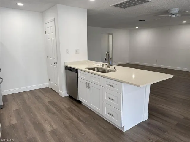Kitchen with recessed lighting, a peninsula, a ceiling fan, dark wood-style flooring, and white cabinets