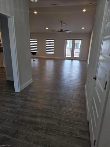 Empty room featuring dark wood-style floors, ceiling fan, recessed lighting, and french doors