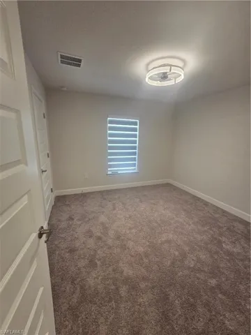 Unfurnished room with dark carpet and baseboards