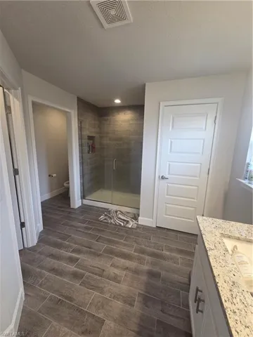 Full bathroom with vanity, a shower stall, wood finish floors, and a textured ceiling
