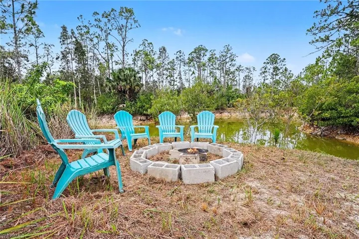 Outdoor fire pit area with an adjacent water feature, surrounded by mature trees