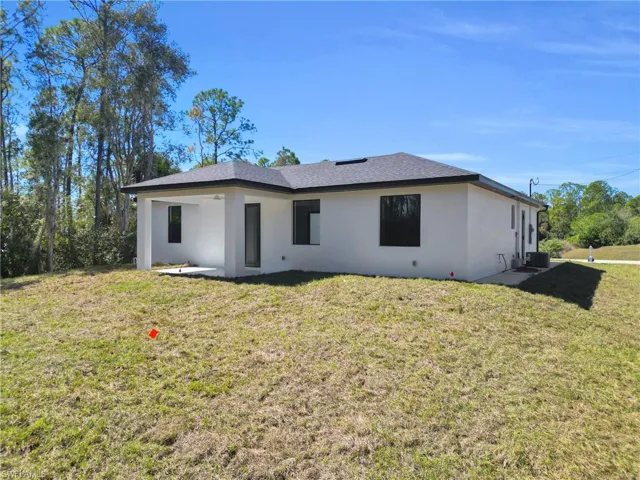 Back of house featuring a lawn, stucco siding, and a patio area