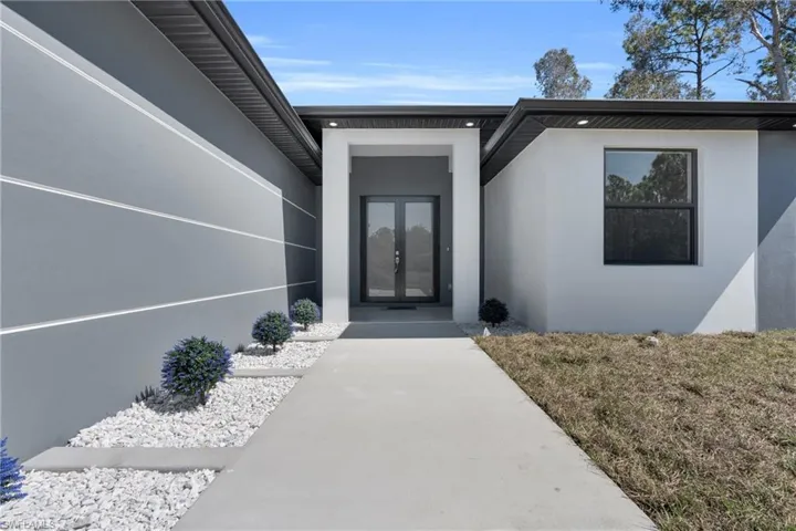 Doorway to property featuring stucco siding and french doors
