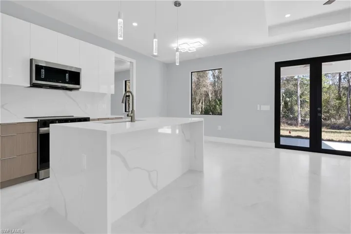Dual tone kitchen with modern cabinets, black range with electric stovetop, light stone countertops, and two tone cabinetry