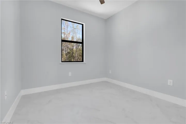 Unfurnished room with light marble finish floors and ceiling fan