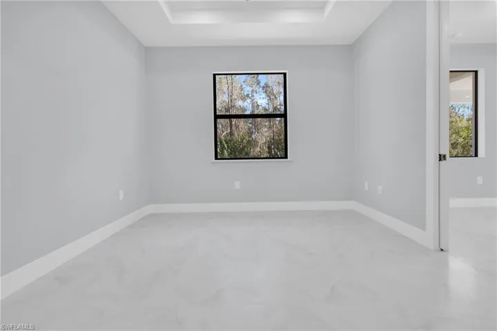 Unfurnished room with baseboards and a tray ceiling