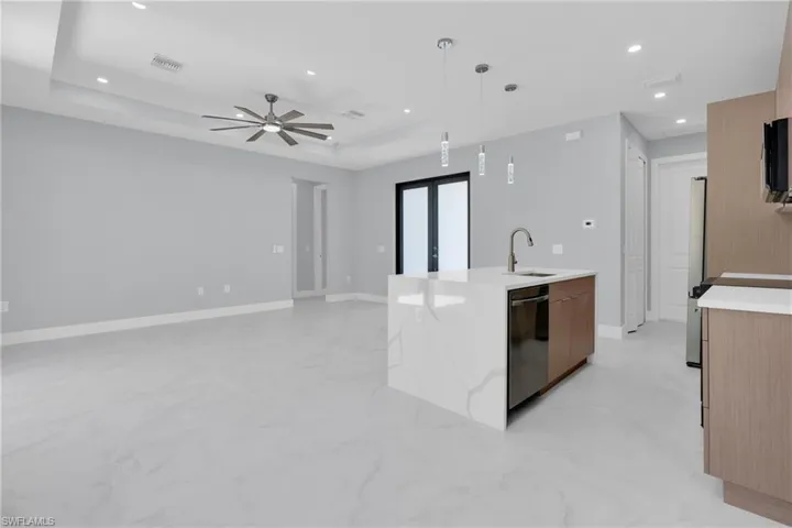 Kitchen with light stone countertops, open floor plan, decorative light fixtures, modern cabinets, and a ceiling fan