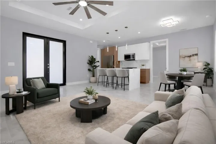 Living room with ceiling fan, french doors, and a raised ceiling