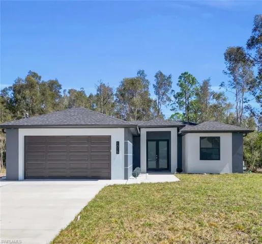 View of front of home with french doors, stucco siding, a garage, concrete driveway, and a front yard
