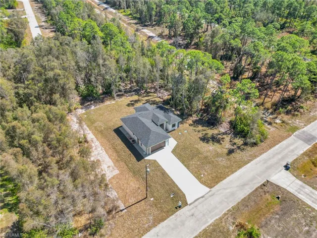 Aerial view of property and surrounding area with a heavily wooded area