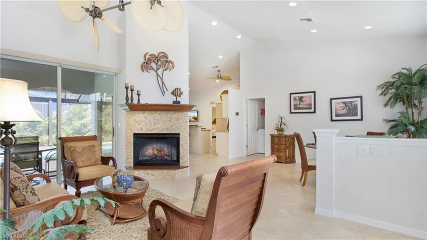 Living room with a tile fireplace, ceiling fan, light tile patterned floors, recessed lighting, and lofted ceiling