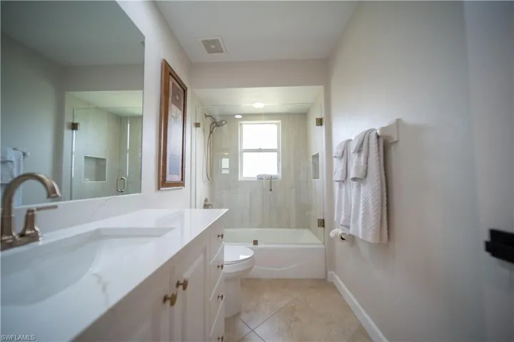Full bathroom with vanity, shower / bath combination with glass door, and light tile patterned floors