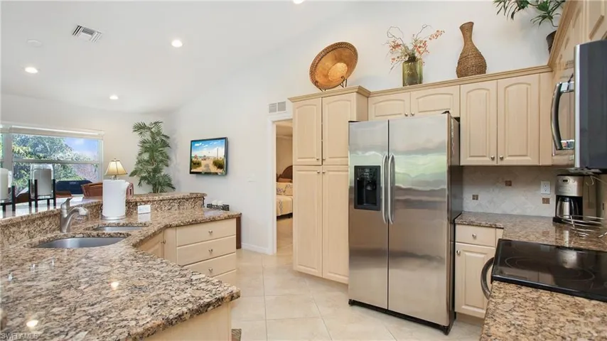 Kitchen with stainless steel appliances, light stone countertops, vaulted ceiling, recessed lighting, and light tile patterned floors