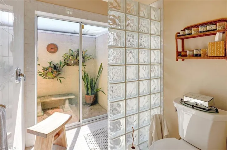 Bathroom with tile patterned floors, a tile shower, and toilet