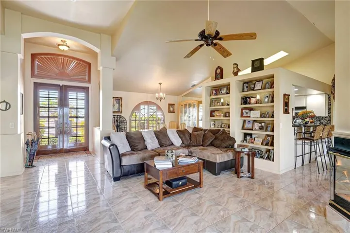Living room with high vaulted ceiling, ceiling fan and built in shelves