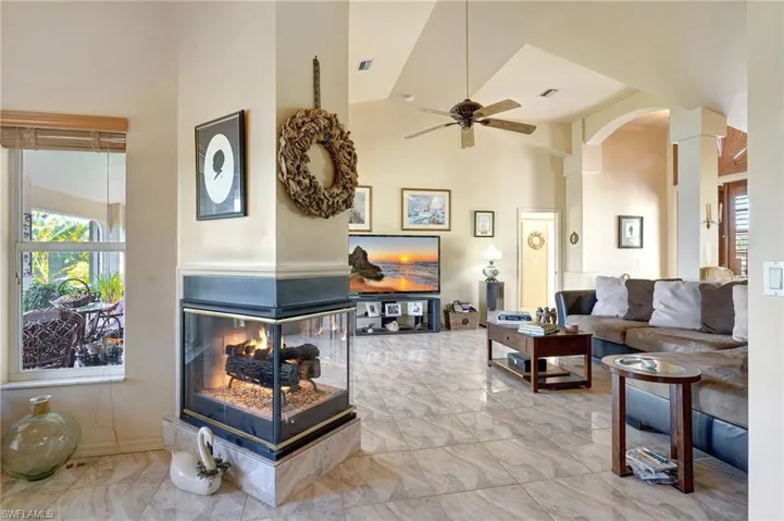 Living room featuring ceiling fan, high vaulted ceiling, and a multi sided fireplace