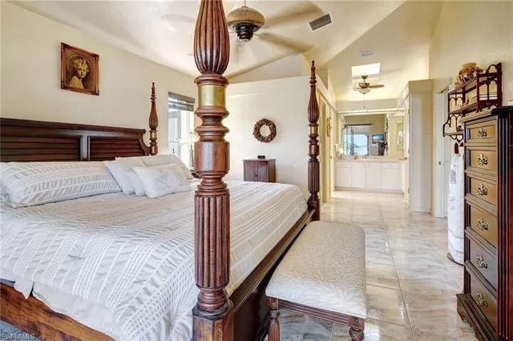 Bedroom with ceiling fan, vaulted ceiling, and ensuite bath