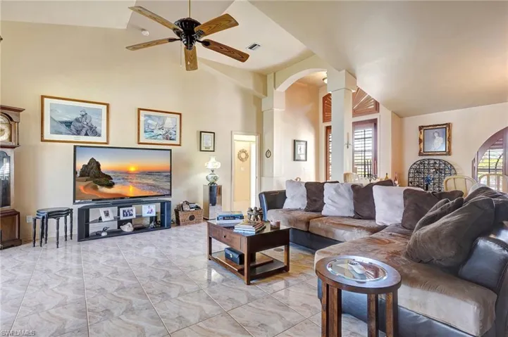 Living room with ornate columns, high vaulted ceiling, plenty of natural light, and ceiling fan