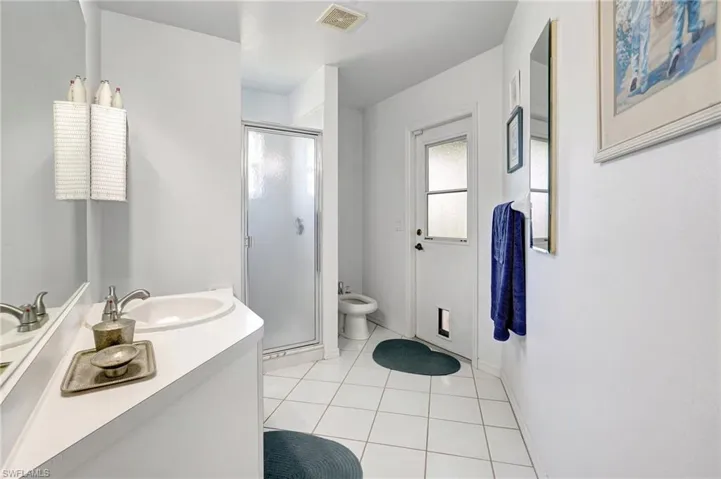 Bathroom with vanity, walk in shower, a bidet, and tile patterned flooring