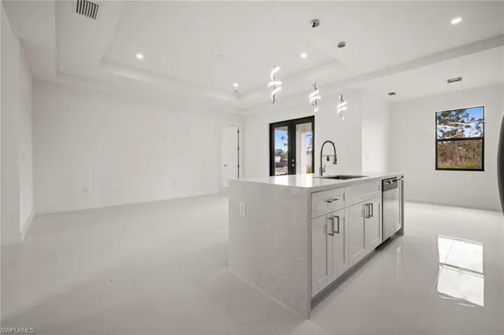 Kitchen with an island with sink, light stone countertops, open floor plan, and hanging light fixtures