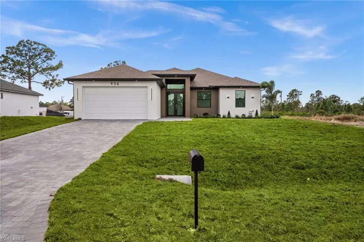 Prairie-style house featuring decorative driveway, an attached garage, stucco siding, a front yard, and french doors