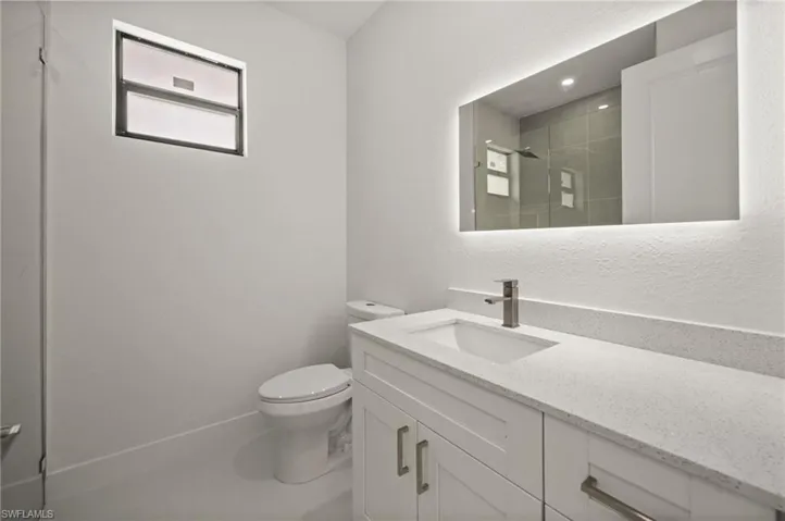 Full bathroom with a textured wall, vanity, and a shower stall