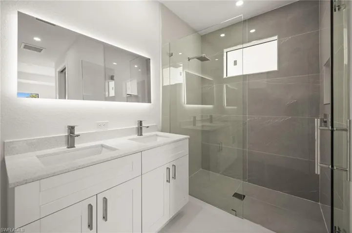 Bathroom featuring double vanity, a shower stall, and recessed lighting