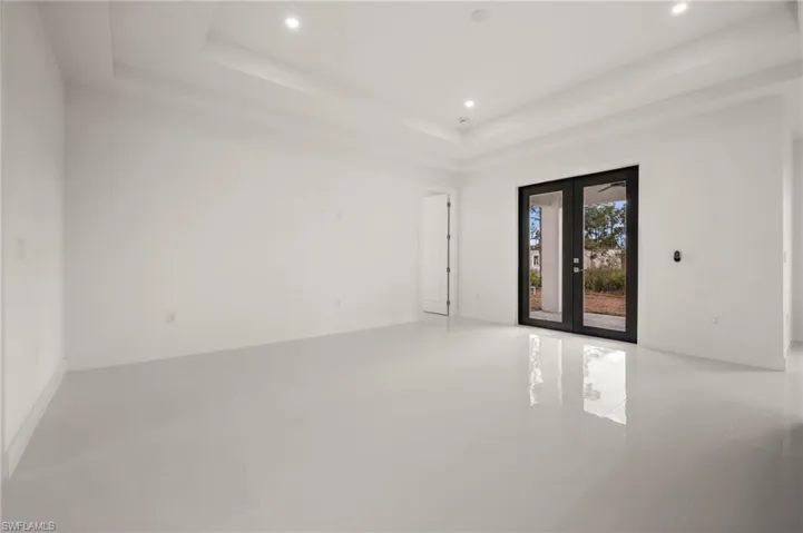 Empty room featuring french doors, recessed lighting, light tile patterned floors, and a raised ceiling