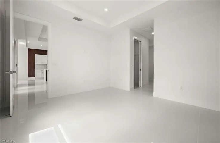 Empty room with recessed lighting, a tray ceiling, and light tile patterned floors