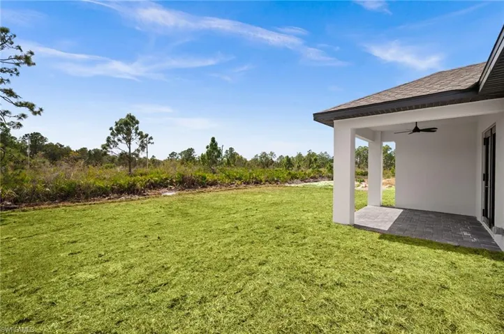 View of green lawn featuring a ceiling fan and a patio