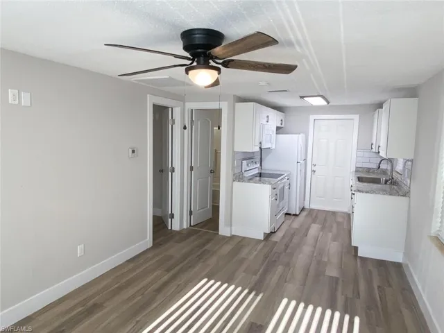 Kitchen featuring dark hardwood / wood-style floors, ceiling fan, sink, and white appliances