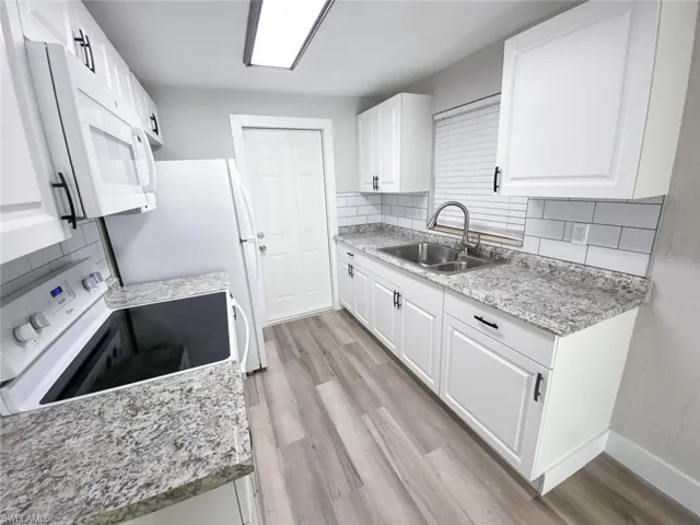 Kitchen featuring white appliances, white cabinets, tasteful backsplash, and light hardwood / wood-style flooring