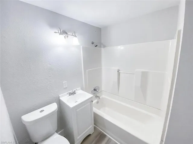 Full bathroom with hardwood / wood-style flooring, vanity, toilet, and shower / bathtub combination