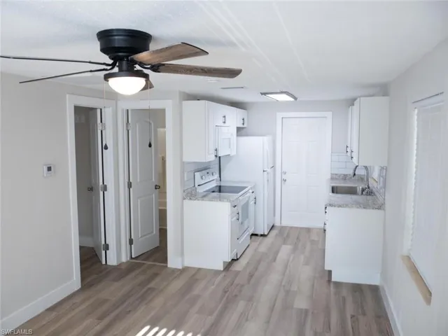 Kitchen with ceiling fan, sink, white appliances, and light wood-type flooring