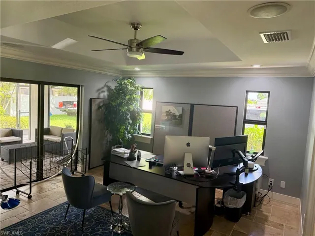 Office space with a ceiling fan, ornamental molding, and stone tile flooring