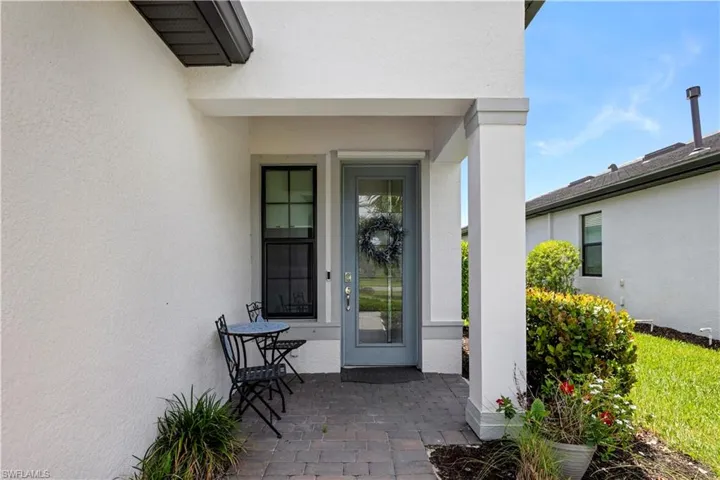 Entryway featuring a light blue door with glass insert, black-framed window, and a paver stone porch