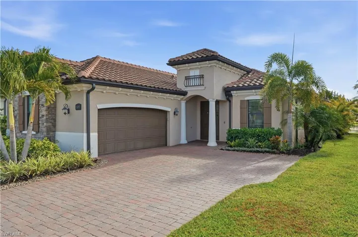 Mediterranean / spanish house featuring an attached garage, stucco siding, decorative driveway, a tiled roof, and a front lawn