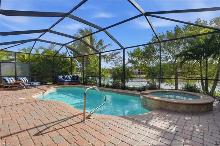 Combined pool / hot tub with a sunroom, a lanai, a water view, and a patio area