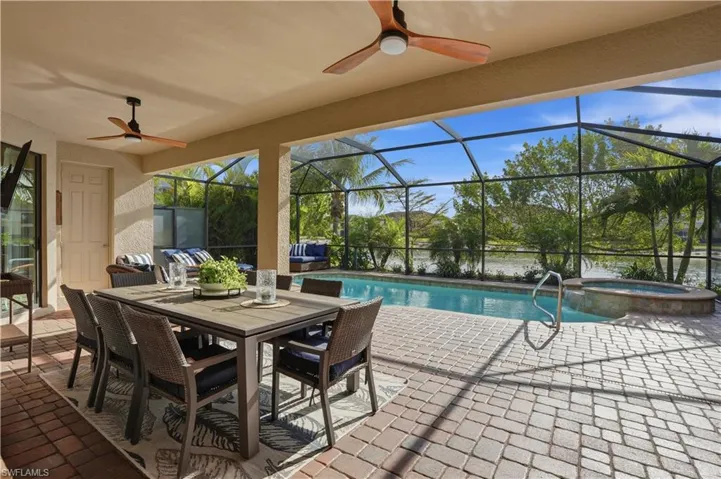 Integrated pool / hot tub with a patio area, a sunroom, outdoor dining space, a lanai, and a water view