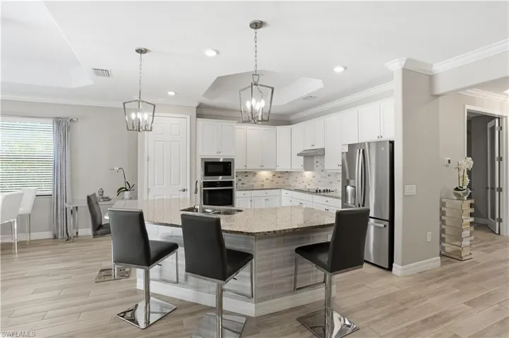 Kitchen with a kitchen bar, stainless steel appliances, light stone counters, tasteful backsplash, and light wood-type flooring