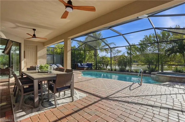 Combined pool / hot tub with a patio area, outdoor dining space, a sunroom, and a lanai