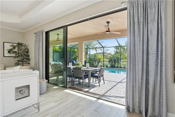 Doorway with a sunroom, wood tiled floors, a tray ceiling, crown molding, and a ceiling fan