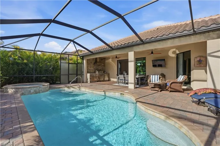 Integrated pool / spa featuring a sunroom, a lanai, an outdoor kitchen / dining area, and a patio